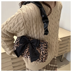 Dettaglio della borsa leopardata con grande fiocco nero e tracolla in pelle a pieghe