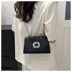 Detail of elegant black leather crossbody bag featuring a large square rhinestone buckle