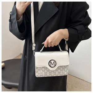 Détail du sac à main blanc avec boucle en métal M ronde et motif imprimé de lettres