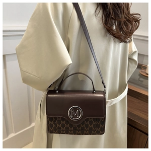 Detail of dark brown leather crossbody bag with M logo and vintage monogram pattern