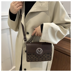 Detail of vintage brown tote bag with M-letter monogram pattern and silver logo buckle