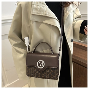 Détail du sac à main marron foncé avec logo M argenté et motif monogramme sur cuir