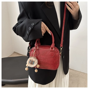 Red leather mini square handbag detail with lucky LHCO embossed text and bear charm