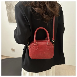 Close-up of retro red matte leather square bag with embossed lettering and top handle