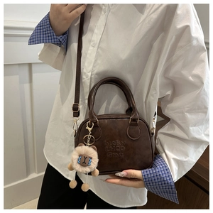 Macro detail of brown leather bag texture with lucky engraving and cute sheep pendant