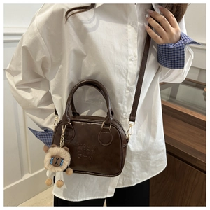 Brown leather crossbody bag detail with Lucky logo and cute plush lamb charm accessory