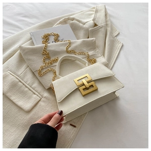 Detail of white PU leather square bag with gold buckle and chain on beige jacket