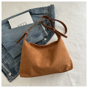 Detail of a large brown suede tote bag featuring a leather strap and gold metal buckle