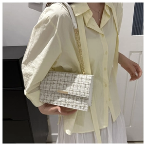 Detailansicht der weißen Tweed-Umhängetasche mit goldener Kette und Metallverzierungen