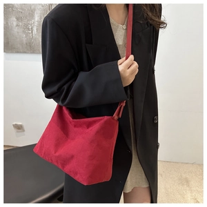Close-up of a vintage red suede shoulder bag worn with a black blazer for a retro look