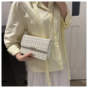 Detailansicht der Damen Tweed-Umhängetasche mit goldener Kette in häuslicher Umgebung