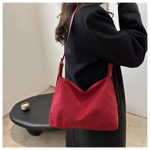 Model view of red suede underarm bag with minimalist shoulder strap and matte finish