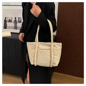 Detail view of a beige quilted tote bag showing its texture and long shoulder straps