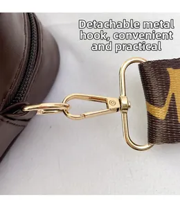 Detail of golden hardware hook and detachable monogram strap on a brown leather bag