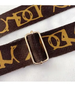 Detail of adjustable wide shoulder strap with vintage gold letter pattern and metallic buckle