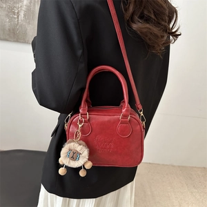 Red square crossbody bag with lucky embossing and plush charm on black blazer