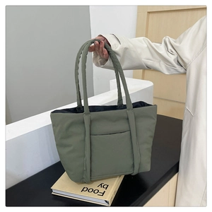 Detail of green quilted puffer tote bag featuring a front pocket and soft texture