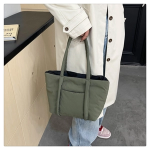 Detailed view of grey-green quilted tote bag featuring a side pocket and puffy texture
