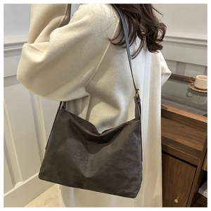 Detail view of dark grey matte suede shoulder bag worn with an elegant wool coat