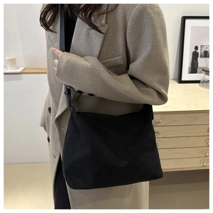 Close-up of minimalist black canvas shoulder bag showing material texture and stitching