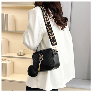 Detail of black V-quilted crossbody bag with gold double S logo and tassel pendant
