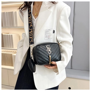 Close-up of black quilted crossbody bag with gold logo, tassels and round coin purse