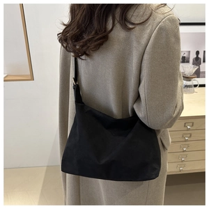 Minimalist black canvas shoulder bag shown from a back side view on a model