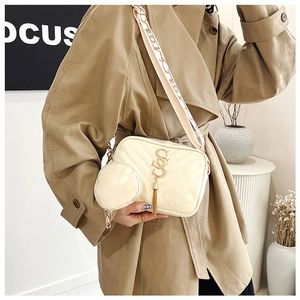 Detail of cream quilted crossbody bag with golden tassel and patterned woven strap