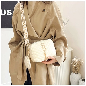 Detail of quilted beige leather crossbody bag with gold tassel and patterned strap