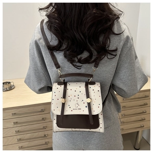 Detail of a chic cream backpack with brown leather accents and rabbit logo on model back