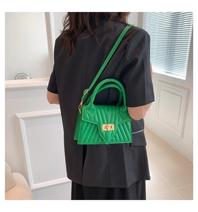 Green crossbody bag with V-quilted texture and gold twist lock shown on model