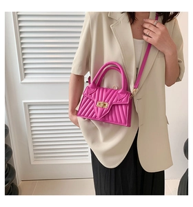 Detail of fuchsia quilted crossbody bag featuring V-stitch texture and metal twist lock