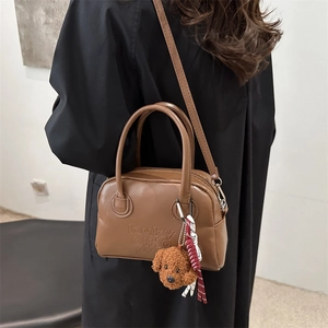 Brown faux leather crossbody bag with embossed letters and teddy bear charm on model