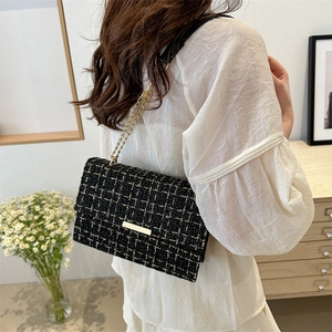 Elegante schwarze Tweed-Umhängetasche mit Goldkette am Model im Freien gezeigt