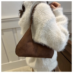 Detail view of the asymmetric trapezoid design and matte dark brown suede texture of the bag