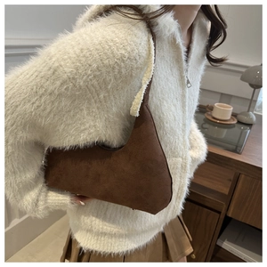 Close-up of brown suede hobo bag with a minimalist half-moon shape and shoulder strap