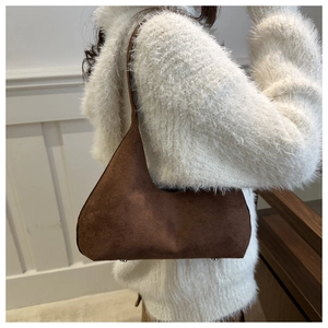 Detail of dark brown suede underarm bag showing matte texture and metal bottom studs
