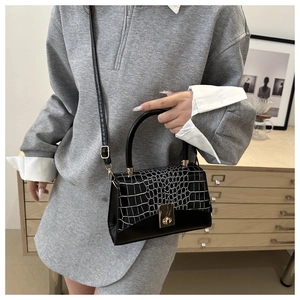 Close-up of black and white crocodile pattern crossbody bag with golden rotary lock