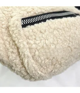 Close-up of soft beige teddy fleece fabric texture with durable black metal zipper