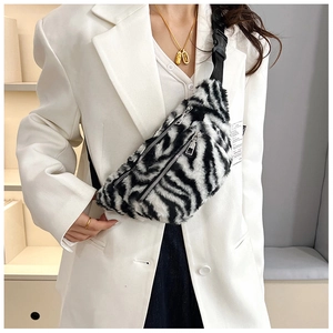 Detail of plush zebra print crossbody bag featuring dual silver zippers and teddy fabric texture