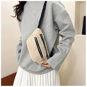 Close-up of off-white faux shearling waist bag with dual zippers and adjustable black strap