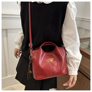 Detail of red matte tote bag with golden metal plate and woven rope charm with small bell