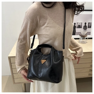 Detail of black wax leather bucket bag with metallic triangle logo and adjustable strap