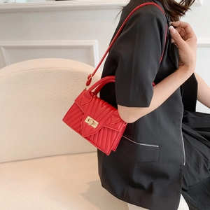 Elegant red V-quilted faux leather handbag with gold turn-lock worn by a model