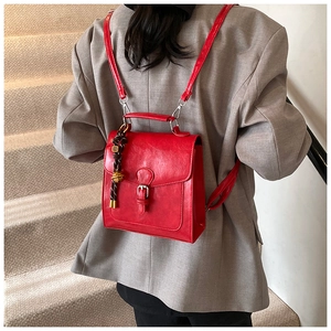 Detail view of red retro PU leather backpack with silver buckle and woven pendant detail