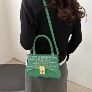 Green women handbag with gold crocodile texture and metal lock shown on a model