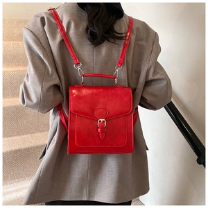 Rear view of a red retro PU leather backpack on a grey blazer with silver hardware