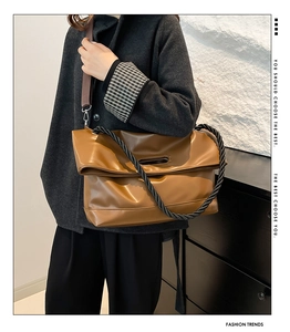 Close-up of brown leather tote bag featuring unique thick black rope handles and long strap