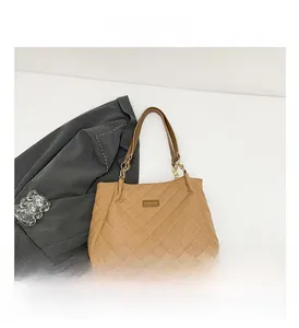 Close-up of khaki quilted tote bag featuring a metal logo and chain strap detail