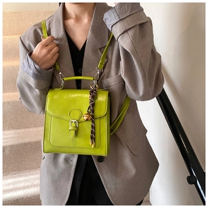 Detail of lime green leather handbag with decorative lanyard worn over grey suit
